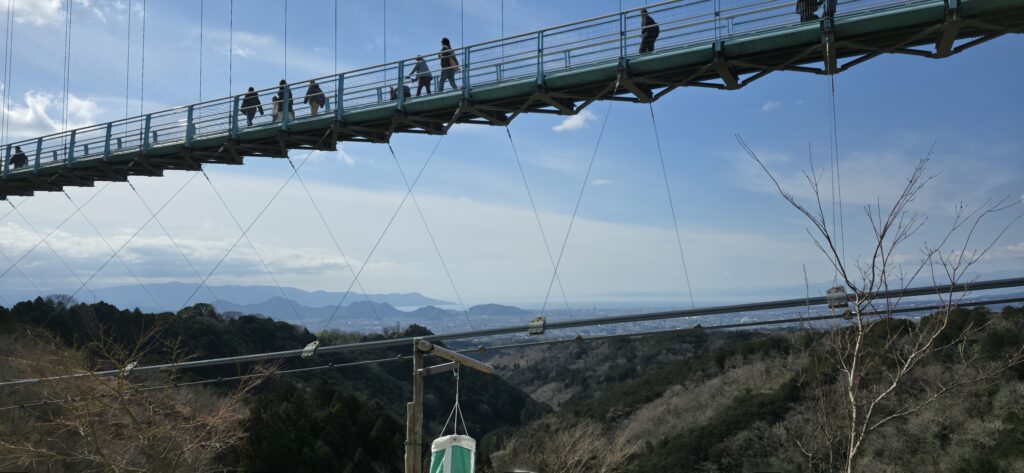 三島スカイウォークのロングジップスライドから見た吊り橋とその奥の駿河湾の絶景